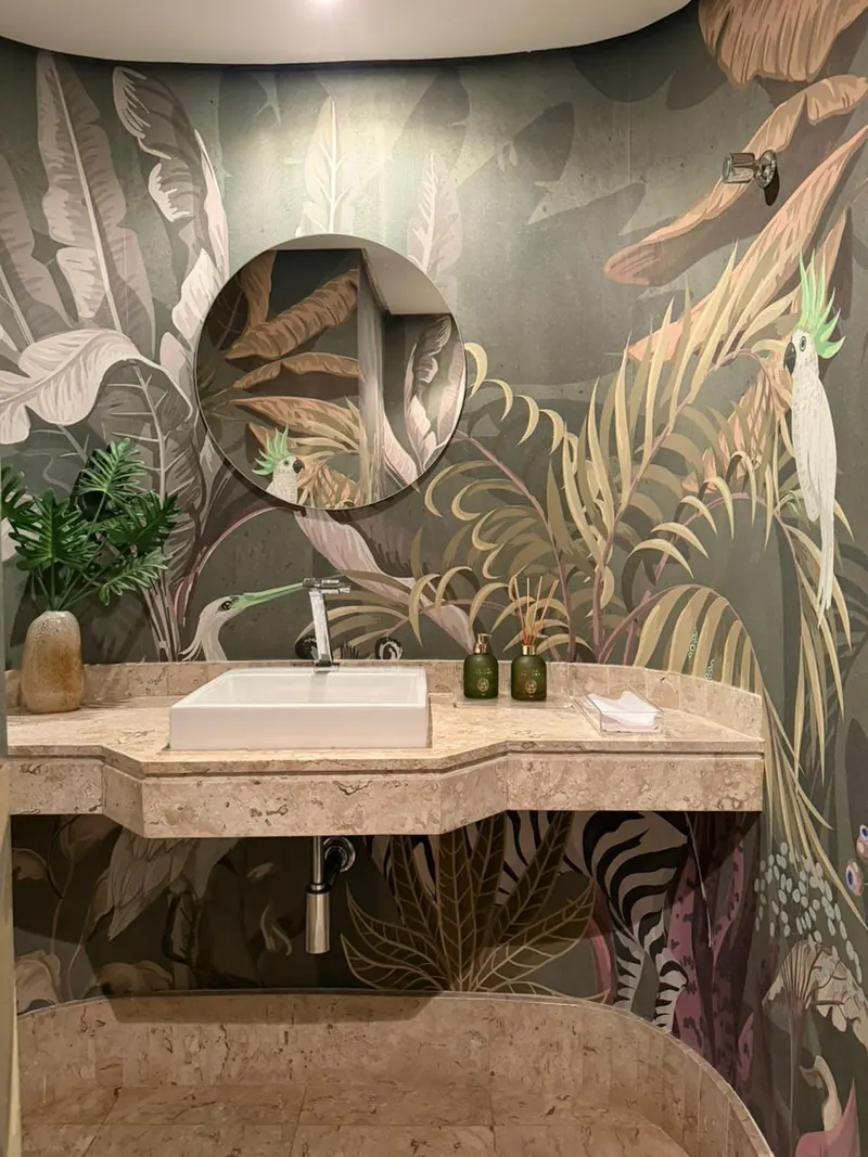 Lavabo com papel de parede de folhagens e bancada de pedra clara