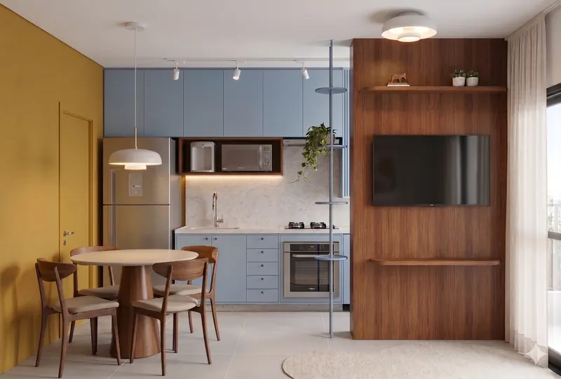 Cozinha de armários azuis integrada à sala com painel de TV