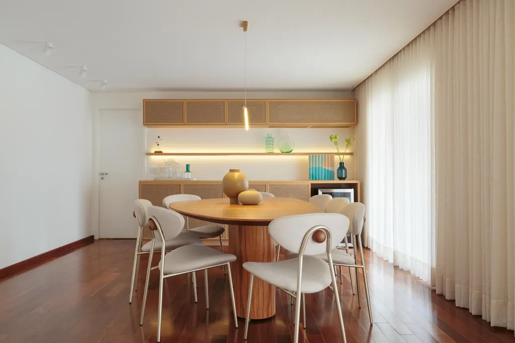 Sala de jantar de apartamento de 250 m² com mesa redonda e estante iluminada