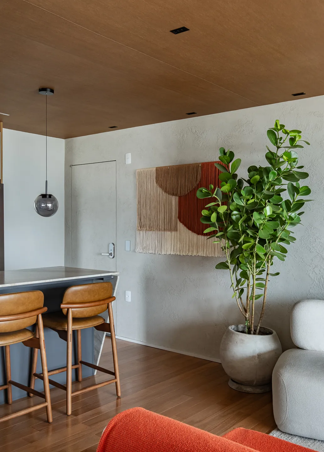 Ilha com banquetas de madeira e painel têxtil na parede
