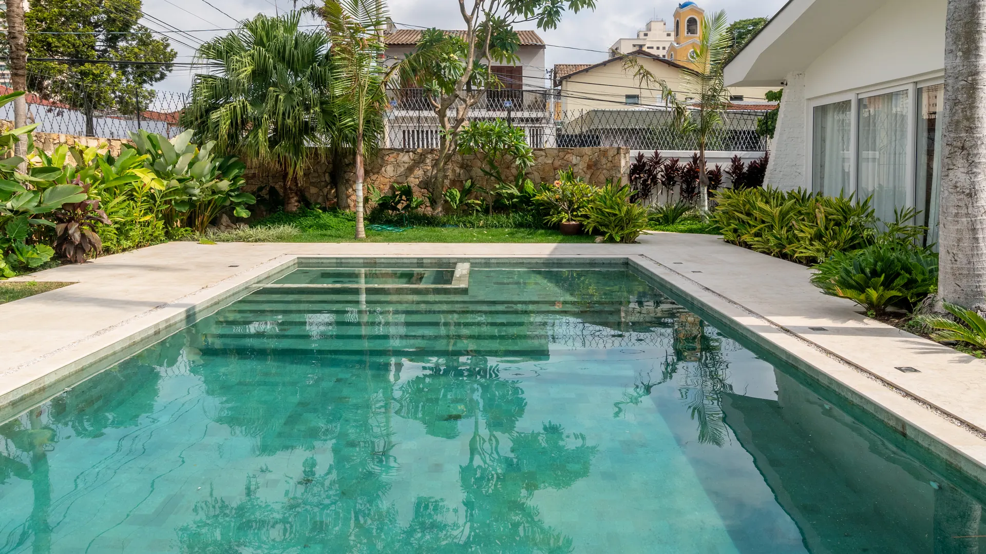 Piscina com borda clara e jardim tropical