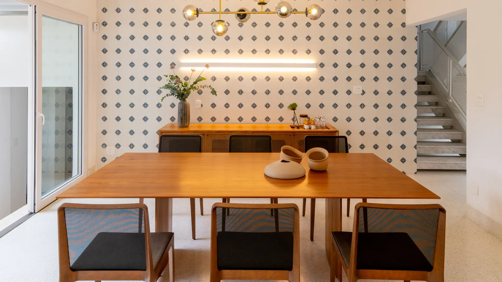 Sala de jantar com mesa de madeira diante de parede de cobogó