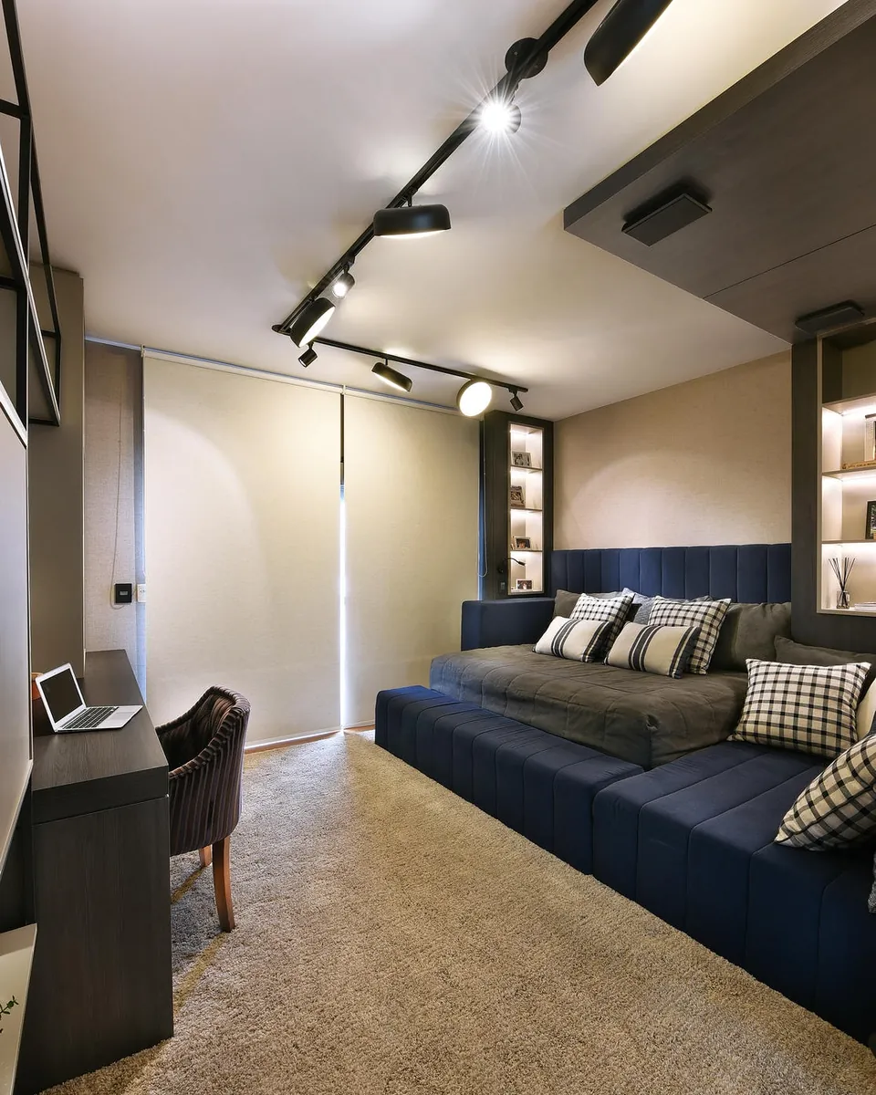 Quarto com estante iluminada, trilho de spots e sofá-cama azul